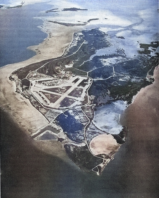 Aerial view of Peleliu in Oct 1946.  Many facilities have been built and the jungle growth has returned to the coral island since the fierce fighting of 1944 stripped it bare.  Even so, the contours of the Umurbrogol Mountains can easily be seen. [Colorized by WW2DB]