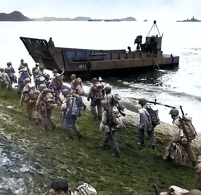 American troops marching up the beach at Adak, Aleutian Islands during pre-invasion loading for the Kiska invasion, 13 Aug 1943; note LCM landing craft, USS Pennsylvania, and M1 Garand rifles [Colorized by WW2DB]