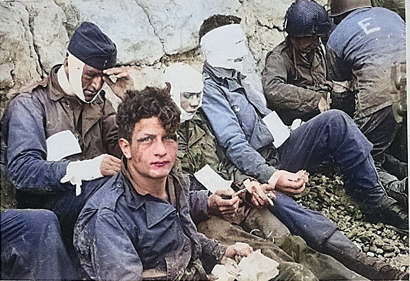 Injured men of the US 16th Infantry Regiment waited by the Chalk Cliffs for evacuation to a field hospital for further medical treatment, Collville-sur-Mer, Normandy, 6 Jun 1944 [Colorized by WW2DB]