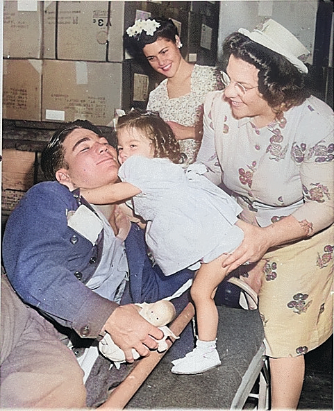 American Private First Class Lee Harper, wounded at Normandy, was greeted by his 2-year-old sister Janet, whom he had never seen before, as his mother and wife looked on, New York City, 1 Aug 1945 [Colorized by WW2DB]