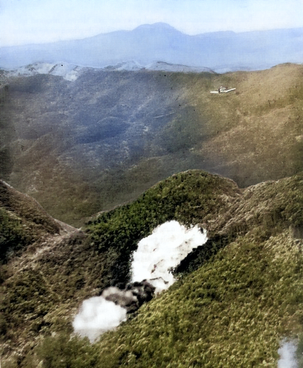 US Marine F4U Corsair fighter dropping a fire bomb on a Japanese position in Northern Okinawa, Japan, circa Apr-Jun 1945 [Colorized by WW2DB]