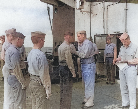 Captain George C. Montgomery awarding a citation ribbon to Aviation Ordnanceman 2nd Class Harvey J. Rowe aboard USS Anzio, 6 Jan 1945, photo 1 of 2 [Colorized by WW2DB]