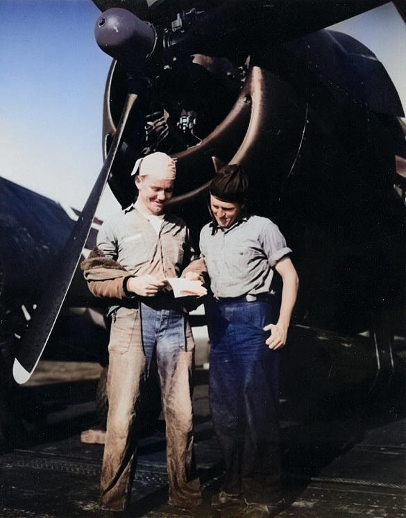 US Navy Seamen 1st Class A. D. Allison and J. W. Roberts reading a letter on Belleau Wood's flight deck next to a F6F Hellcat fighter, circa 1945 [Colorized by WW2DB]