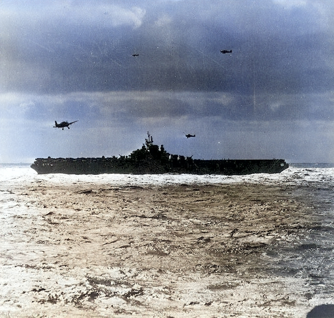 USS Hancock recovering aircraft in the South China Sea, Jan 1945; note three F6F Hellcat and one TBM Avenger aircraft in flight; seen from USS New Jersey [Colorized by WW2DB]