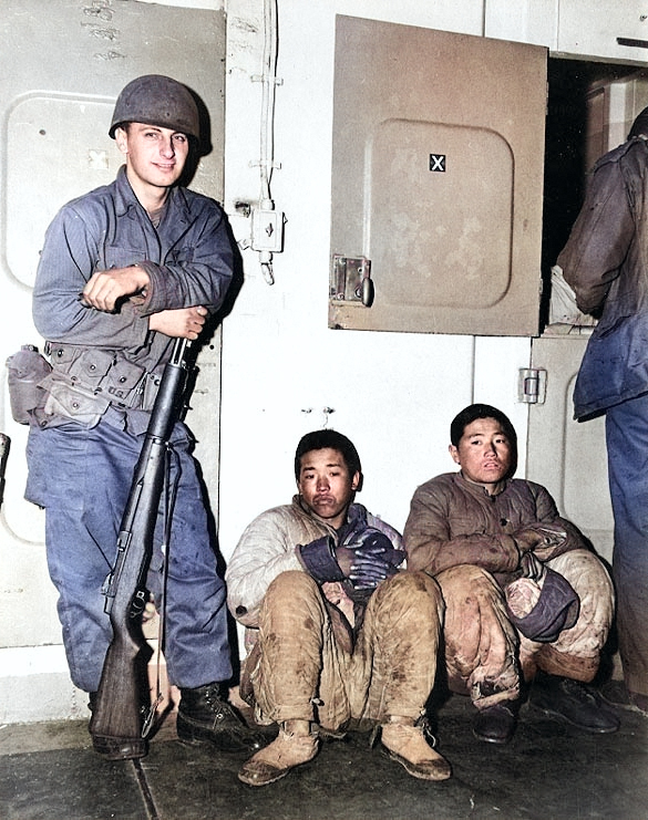 US Marines guarding 2 North Korean prisoners aboard a transport ship which was probably traveling from Hungnam to Busan, Korea, late Dec 1950; note M1 Garand rifle with safety at 'off' position [Colorized by WW2DB]