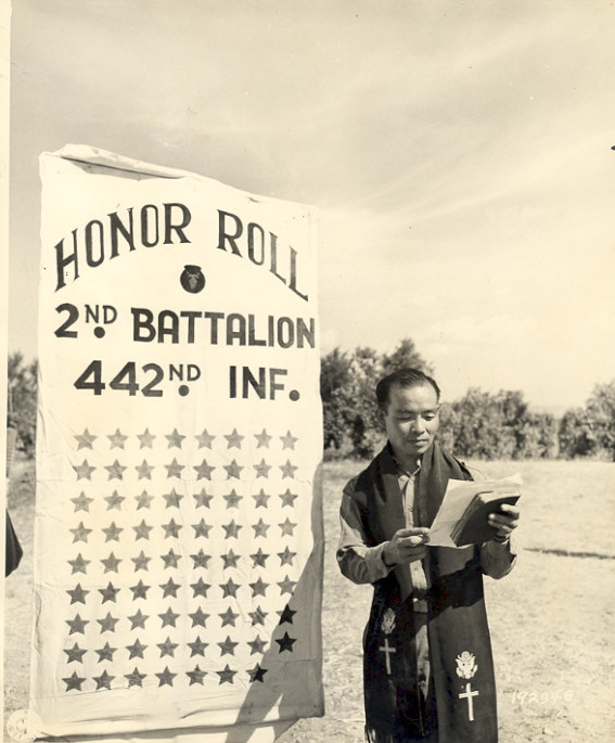 Japanese-American Chaplain Hiro Higuchi of 2nd Battalion, US 442nd Regimental Combat Team reading names of 72 fallen soldiers, Cecina area, Italy, 30 Jul 1944