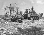 US Marine Corps M4 Sherman tank blasts a Japanese pillbox in advance of 3rd Division infantry on Guam, Mariana Islands, Aug 1944. Note combat cameraman with hand-held movie camera standing behind the tank