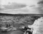 Damaged and abandoned LVTs sink into the sand as beach activity continues on Iwo Jima, Feb 1945.