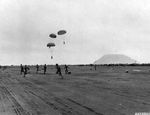 Marines recovering parachute packs with mail and mortar shells, Iwo Jima, Mar 1945. Note Mt Suribachi.