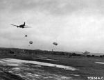 A Curtiss R5C Commando after releasing parachute packs with supplies for construction units repairing the main airstrip on Iwo Jima, Bonin Islands. Mar 6, 1945. Note B-29 Superfortress on the ground.