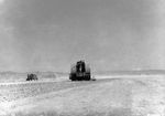 US Marine engineers working to repair the main airfield on Iwo Jima are forced to take cover behind their vehicles during a mortar attack, Mar 1945.