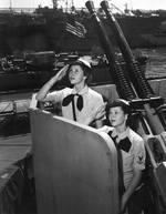 WAVES Yeoman Second Class Blanche Oswald and Yeoman Third Class Betty Martin aboard USS Missouri, Norfolk Navy Yard, Virginia, United States, 19 Aug 1944. Note USS Alaska and escort carrier USS Croatan.