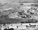 Aerial view of the Pearl Harbor Submarine Piers at Merry Point, 13 Oct 1941. Also pictured is the U-shaped Headquarters Building for the Pacific Fleet and a tank farm at right. Note one tank painted as a building.