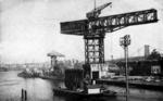 The bow of USS Hornet being transported out of New York Navy Yard, Brooklyn, New York, United States, May 1952; note USS Ticonderoga in right background; seen in Oct 1957 issue of All Hands magazine