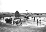 A P-47 Thunderbolt making a low pass over the bombers of the 306th Bomb Group at RAF Thurleigh, Bedfordshire, England in Jun or Jul 1943. Note the Cletrac tractor towing the bomber into its stand.