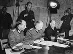 German Colonel General Alfred Jodl (center) signing the surrender document at Dwight Eisenhower