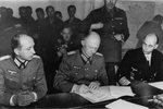 German Colonel General Alfred Jodl (center) signing the surrender document at Dwight Eisenhower