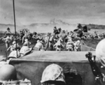 Men of the US 4th Marines rushing out of their landing craft for Iwo Jima landing beach, 19 Feb 1945, photo 2 of 2; note LVT burning in right center