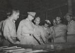 Richmond Kelsey (far left), Douglas MacArthur (second from left), Amor Sims (second from right), and others studying a relief map of Cape Gloucester, New Britain, 14 Dec 1943