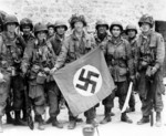 Paratrooper of US 101st Airborne Division holding a Nazi German flag captured in a village near Utah Beach, Saint-Marcouf, France, 8 Jun 1944