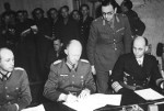 German Colonel General Alfred Jodl (center) signing the surrender document at Dwight Eisenhower