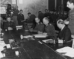 German Colonel General Alfred Jodl (center) signing the surrender document at Dwight Eisenhower