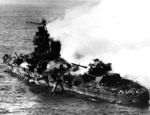 Mikuma burning, with midships structure shattered and torpedo dangling from tube, 6 Jun 1942