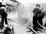 Crewmen of USS St. Louis fighting fires in the hangar, after the ship was struck by a special attack airccraft off Leyte, Philippine Islands, 27 Nov 1944; note wrecked SOC aircraft in background