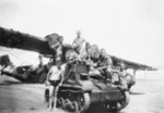 Australian soldiers posing with a captured Japanese Type 92 tankette and wrecked No. 42 Squadron RAAF Catalina aircraft, Balikpapan, Borneo, 1945