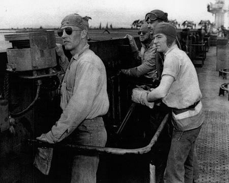 Bob Christensen, Jim Bough, L. D. Smith, and Frank Schwartz manning the arresting gear controls aboard USS Anzio, 20 Apr 1945