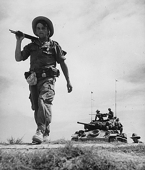 A soldier of the French Foreign Legionnaire in the Red River Delta, between Haiphong and Hanoi, Vietnam, circa 1954; note American-built M24 Chaffee light tank in background