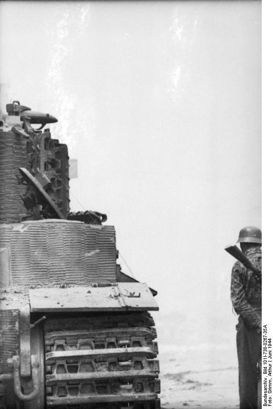 German soldier standing next to a wrecked Tiger I heavy tank, Villers-Bocage, France, Jun 1944