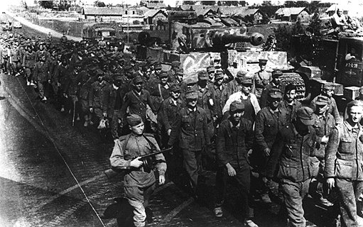 German prisoners on the Minsk-Smolensk highway, Jul 1944; note Russian soldier with PPSh-41 submachine gun in foreground and abandoned Tiger I heavy tank in background