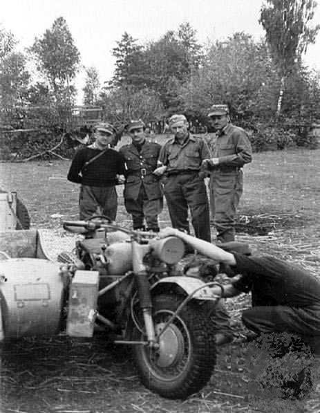 Polish resistance fighters Aleksander Wolski, Olsza, Jan Dabroski, and Stefan Iwanowski inspecting a captured German R75 'Sahara' motorcycle, Warsaw, Poland, Sep 1944